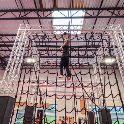 Kid building confidence by climbing a rope obstacle at ninja summer camp in Stafford, Virginia